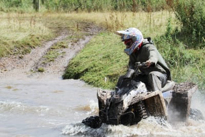 A man riding a quad bike through a river
