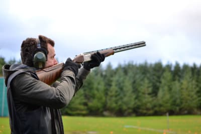 A man shoots a shotgun during clay pigeon shoot